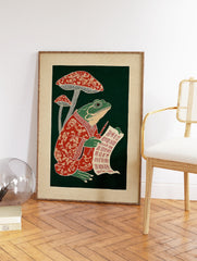 Illustrative frog in a red robe writing on a scroll next to red mushrooms against a dark green background, folk art print. - Image 2