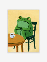 Illustrative art print of a green frog sitting at a round wooden table with a white coffee cup against a yellow background