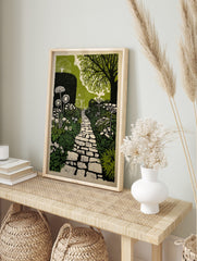 Illustrative garden path print with winding stone pathway, lush green foliage, and white, in an alternate framed mockup