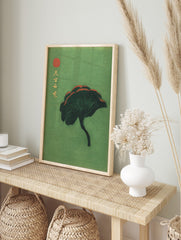 Dark green ginkgo leaf with red accents, Japanese text, and red seal on a green background, in an alternate framed mockup