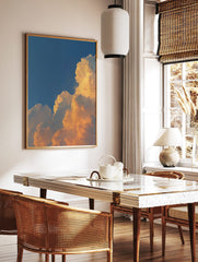 Dramatic golden cumulus clouds against a deep blue sky, capturing a vibrant sunset or sunrise, in a styled room mockup
