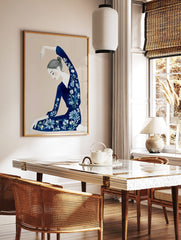 Illustrative art print of a woman in a navy floral outfit with arm raised, on a beige background, in a styled room mockup