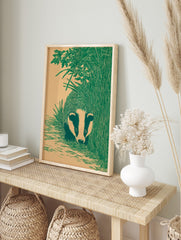 Illustrative green badger peeking from tall grass and foliage on a beige background, portrait, in an alternate framed mockup