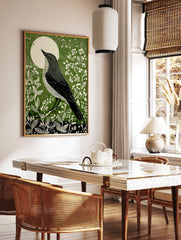Illustrative green bird art print looking at a white moon, surrounded by white botanical plants, in a styled room mockup
