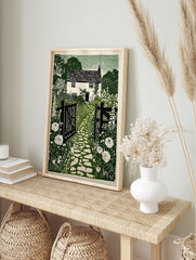 Green and white linocut style print of a cottage garden with a stone path, open gate, and, in an alternate framed mockup