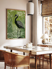 Green and white linocut style print of a black crane bird in reeds and water with a white flower, in a styled room mockup