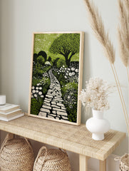 Green and black linocut print of a winding stone garden path surrounded by white flowers and, in an alternate framed mockup