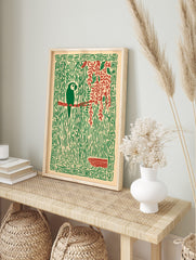 Stylised green parrot on red branch, surrounded by green jungle vines, red leaves, and a, in an alternate framed mockup