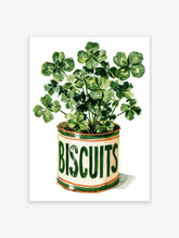 Watercolour clover plant in a cream biscuit tin with green BISCUITS lettering and orange bands