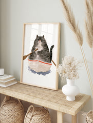 Watercolor illustration of a grumpy fat cat in a small rowing boat on a white background, in an alternate framed mockup