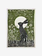 Green linocut print of a black hare sitting in wildflowers under a full moon, capturing a serene nocturnal scene.