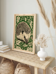 Hedgehog linocut style wall art print with green foliage on a cream background, portrait, in an alternate framed mockup