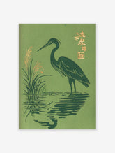Japanese woodblock-style print of a dark green heron wading in water with golden reeds and kanji text