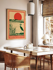 Illustrative art print of a dark green heron by a lake with reeds, rolling green hills, and a large, in a styled room mockup