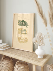 Three stylised Highland cows in green and gold, with leafy and plaid patterns, on a beige, in an alternate framed mockup