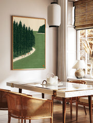 Illustrative wall art of hikers on a sandy path next to a green pine forest and water, in a styled room mockup