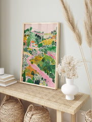 Illustrative landscape art print with a white house, orange roof, green fields, and a winding, in an alternate framed mockup