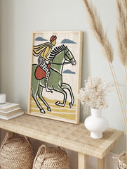 Illustrative print of a rider on a green horse with yellow cape and patterned trousers, in an alternate framed mockup