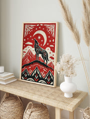 Illustrative red, black, and off-white art print of a howling wolf on a mountain under a, in an alternate framed mockup