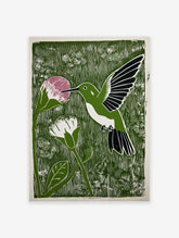 Green linocut print of a hummingbird with a pink flower, white flower, and foliage.