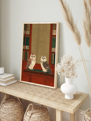 Two illustrative owls on a wooden shelf, flanked by bookshelves with green and Japanese, in an alternate framed mockup