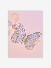 Iridescent butterfly with pearl beads and stained-glass wings on a pink background beside a goblet
