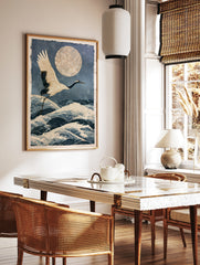 Japanese crane in flight over stylized ocean waves and a large textured moon in an illustrative, in a styled room mockup