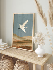 White crane in flight over earthy hills, Japanese-inspired nature wall art print, in an alternate framed mockup