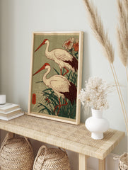 Two Japanese cranes with red beaks and dark tails stand in green reeds, woodblock print style, in an alternate framed mockup