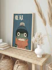 Japanese frog art print featuring a green frog wearing a blue knit hat with a pompom and an orange scarf on a blue background. - Image 3