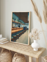 Japanese Izakaya interior art print with patrons and staff at a long wooden counter, shelves, in an alternate framed mockup