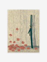 Japanese Katana wall art print with a samurai sword, dark green scabbard, and red maple leaves on a light wood background.