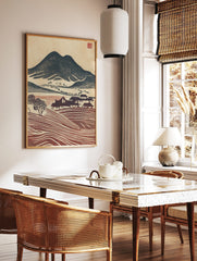 Japanese woodblock style landscape print with dark mountain, village houses, and reddish-brown, in a styled room mockup