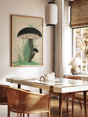 Japanese woodblock-style print of two dark-capped mushrooms with gills, surrounded by green grass, in a styled room mockup