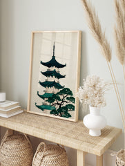 Illustrative Japanese pagoda with teal roofs and a green pine tree on a cream background, in an alternate framed mockup