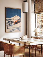 Japanese woodblock style print of a snowy mountain, traditional house with red roof, and pine trees, in a styled room mockup