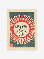 A vibrant Japanese folk art print of a smiling sun with red rays and a dark blue background on textured paper, with a red seal.
