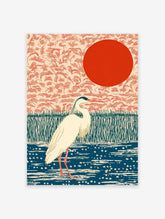 Japanese wall art print of a white heron bird in a blue pond with green reeds and a red sun against a peach sky.