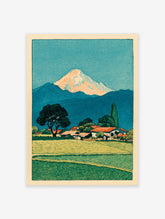 Japanese woodblock print of Mount Fuji over a village with green fields and a large tree in the foreground.