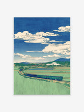 Japanese landscape wall art print with a train winding through green rice fields, mountains, and a blue sky with white clouds.