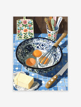 Illustrative kitchen baking scene with eggs, whisk, butter, and floral cutting board on blue tiles, kitchen wall art.