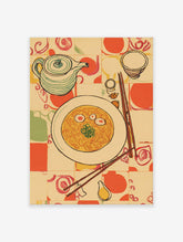 Illustrative kitchen wall art featuring a bowl of noodles, teapot, and chopsticks on a patterned tablecloth.