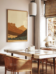 Minimalist illustrative art print of a layered desert mountain landscape with warm earth tones and, in a styled room mockup