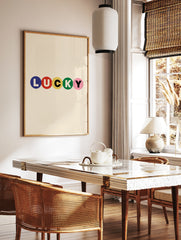 Typography wall art with the word LUCKY in blue, red, yellow, green, and pink circles on a cream, in a styled room mockup