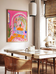 Vibrant illustrative print of a Moroccan archway interior with pink walls, palm tree, and blue, in a styled room mockup