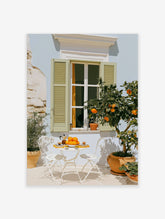 Mediterranean patio with orange tree, white bistro table, and pale blue shutters