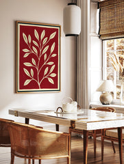 Minimalist botanical wall art with a cream-coloured leafy branch on a solid deep red background, in a styled room mockup
