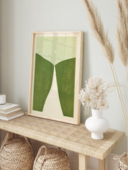 Minimalist abstract art print with rolling green hills, a white path, and a pale circle on a, in an alternate framed mockup