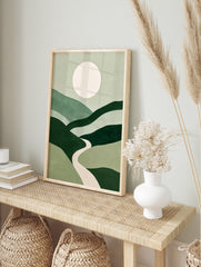 Minimalist green landscape wall art with rolling hills, a central winding path, and a large, in an alternate framed mockup