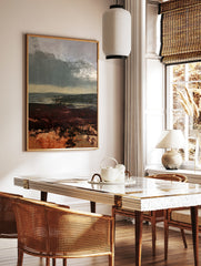 Moody moorland landscape painting with dark sky and deep red heather foreground, atmospheric nature, in a styled room mockup